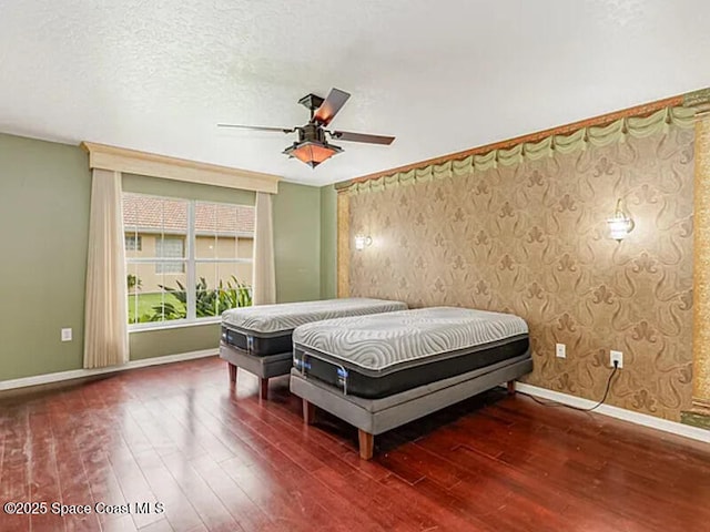 bedroom with hardwood / wood-style floors, ceiling fan, baseboards, and a textured ceiling