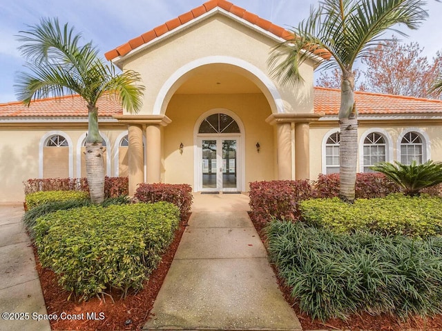 doorway to property with french doors, stucco siding, and a tiled roof