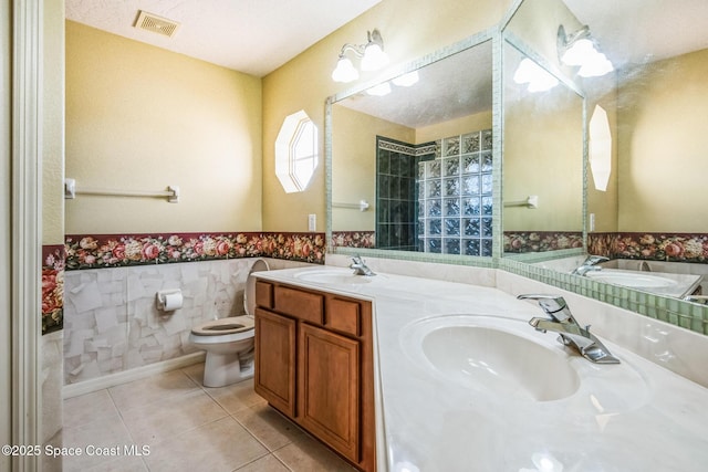 full bath with a sink, tile patterned floors, visible vents, and wainscoting