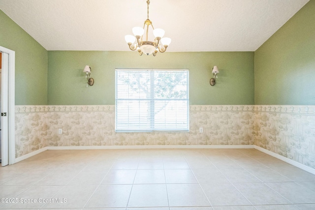 tiled spare room featuring baseboards, a notable chandelier, wainscoting, and wallpapered walls