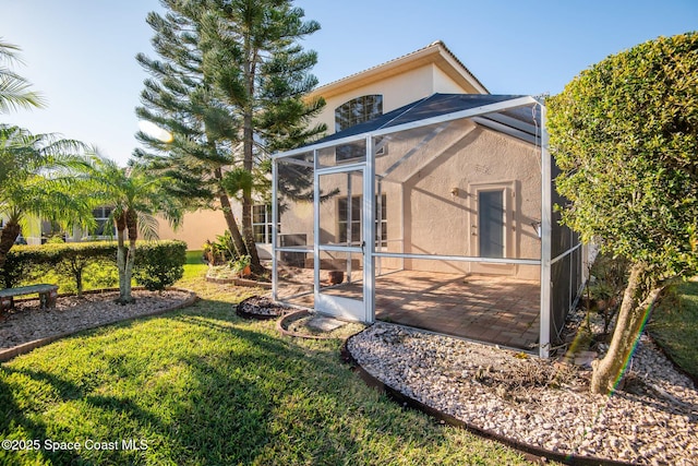 rear view of property featuring stucco siding, a lawn, and glass enclosure