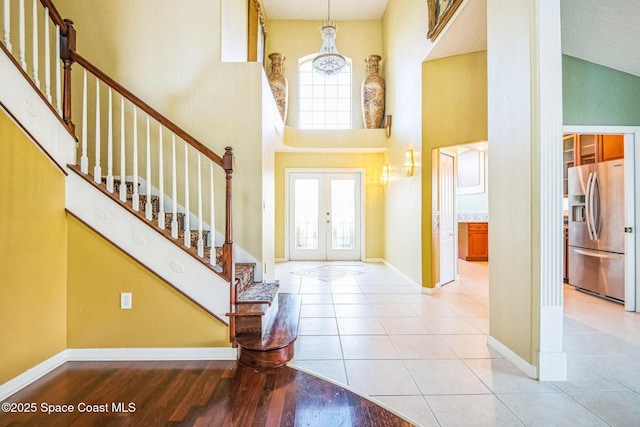 foyer featuring stairs, french doors, a towering ceiling, and a healthy amount of sunlight