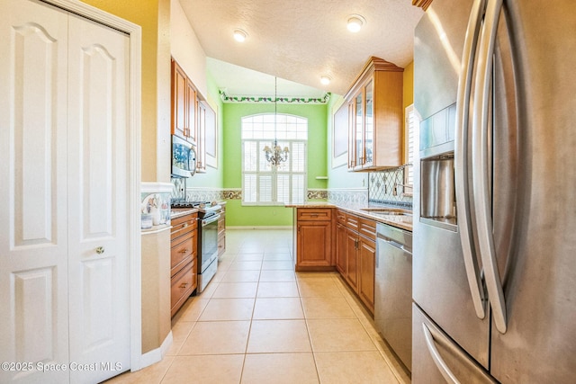 kitchen with brown cabinets, appliances with stainless steel finishes, light tile patterned flooring, glass insert cabinets, and vaulted ceiling