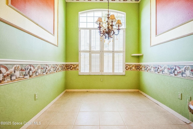 empty room featuring a wealth of natural light, a notable chandelier, tile patterned flooring, and a wainscoted wall