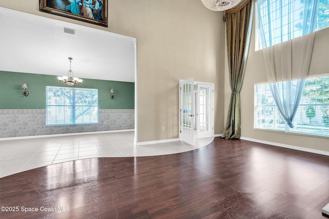 interior space with a wealth of natural light, tile patterned flooring, an inviting chandelier, and a towering ceiling