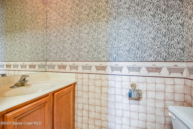 bathroom with wallpapered walls, toilet, and vanity