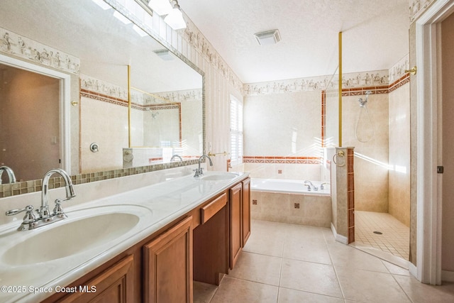 full bath featuring visible vents, a bath, tile patterned floors, a textured ceiling, and a sink