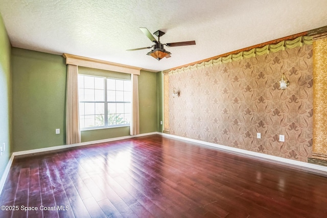 unfurnished room featuring a textured ceiling, wood finished floors, wallpapered walls, baseboards, and ceiling fan