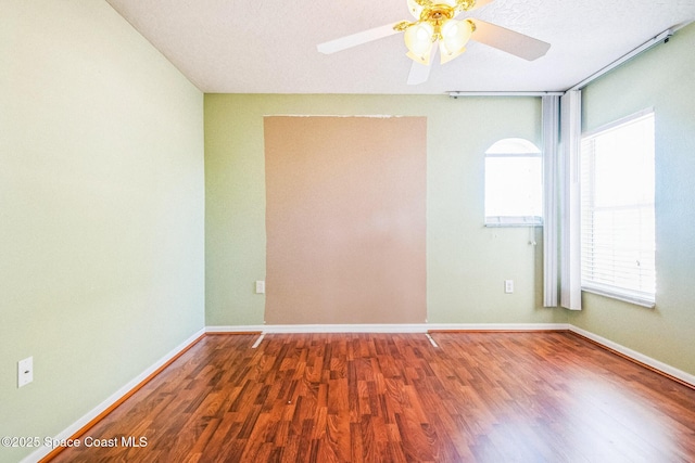 unfurnished room featuring a ceiling fan, wood finished floors, and baseboards