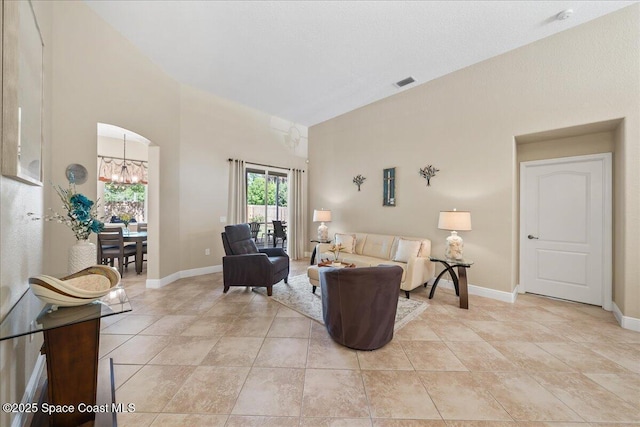 living area with arched walkways, visible vents, baseboards, and a towering ceiling