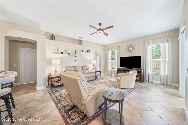 living room featuring light tile patterned floors, visible vents, baseboards, and ceiling fan