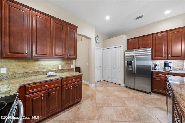 kitchen featuring visible vents, tasteful backsplash, stainless steel appliances, arched walkways, and light stone countertops