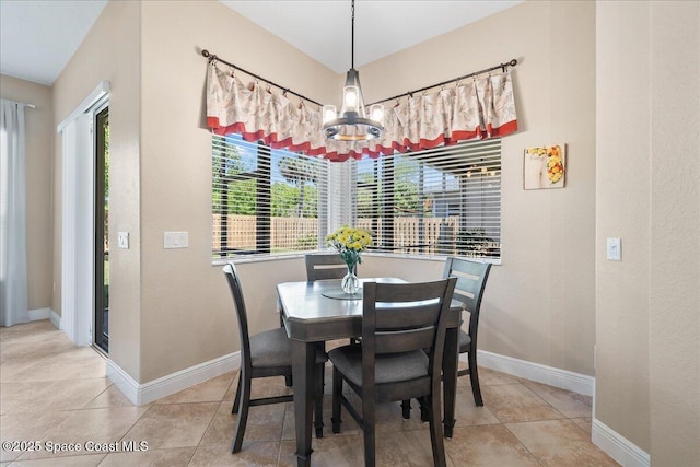 dining room featuring light tile patterned floors, baseboards, and a notable chandelier