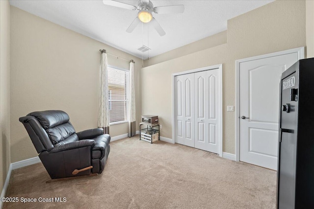 sitting room with ceiling fan, carpet, visible vents, and baseboards