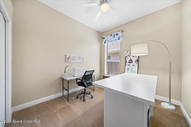 carpeted home office featuring baseboards and ceiling fan