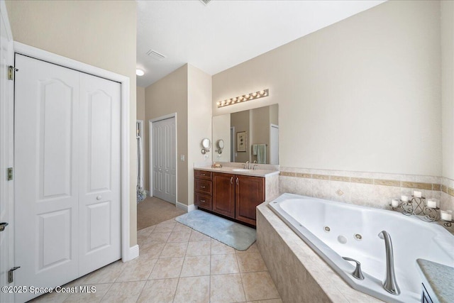 full bathroom featuring a closet, vanity, a whirlpool tub, and tile patterned flooring