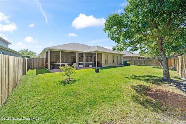 rear view of property featuring a lawn, a fenced backyard, and a sunroom