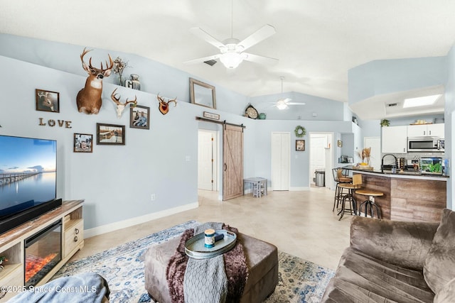 living room featuring a barn door, lofted ceiling, baseboards, and a ceiling fan