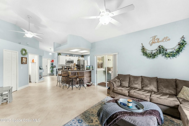 living area with light tile patterned floors, baseboards, lofted ceiling, and ceiling fan