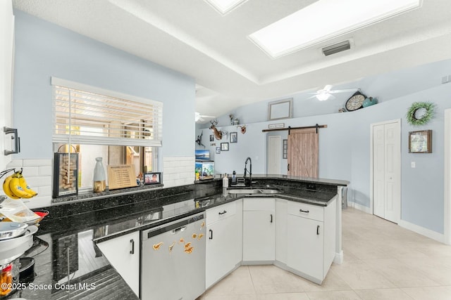 kitchen featuring a sink, stainless steel dishwasher, a barn door, a peninsula, and ceiling fan