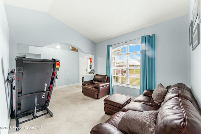 living room with light tile patterned floors, baseboards, arched walkways, and vaulted ceiling