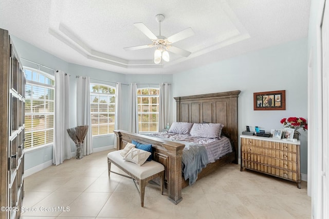 bedroom featuring baseboards, a raised ceiling, a textured ceiling, and ceiling fan