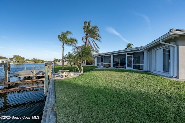 view of yard featuring a water view, a dock, and a sunroom