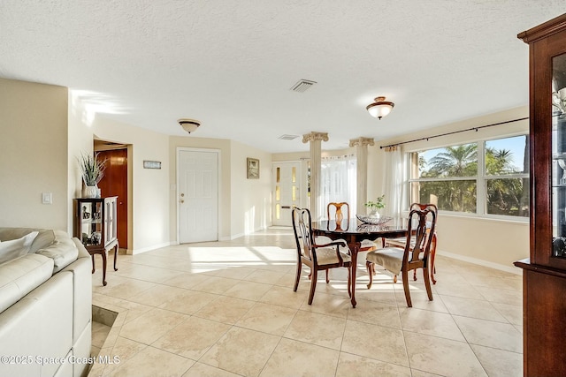 dining area featuring light tile patterned flooring, visible vents, a textured ceiling, and baseboards