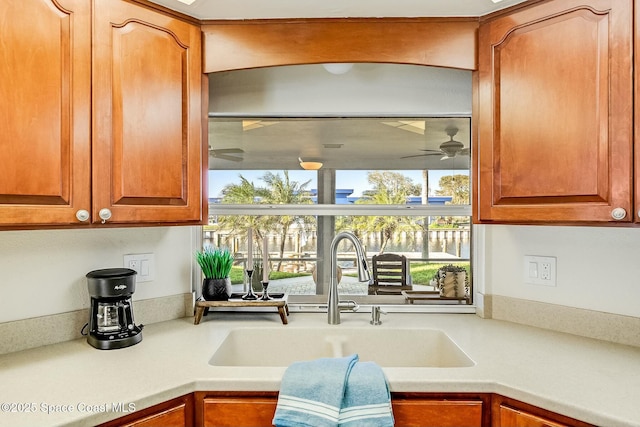 kitchen featuring brown cabinets, light countertops, a ceiling fan, and a sink