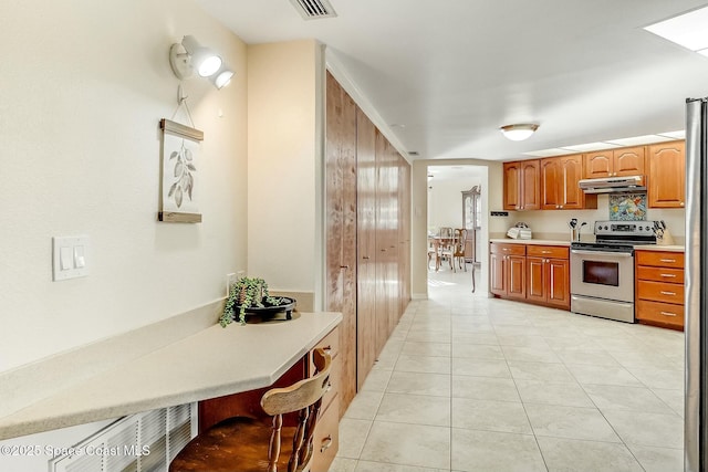 kitchen featuring visible vents, stainless steel electric stove, light tile patterned flooring, light countertops, and under cabinet range hood