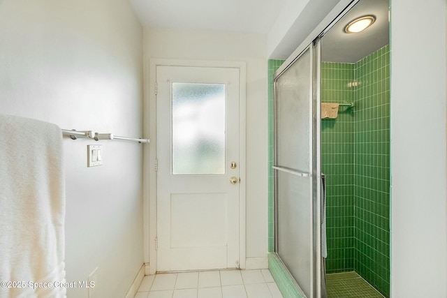 bathroom with tile patterned floors, a shower stall, and baseboards