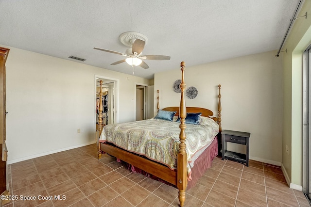 bedroom with visible vents, baseboards, ceiling fan, light tile patterned floors, and a textured ceiling