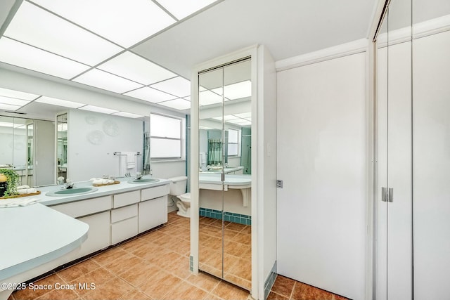 full bath featuring double vanity, toilet, a drop ceiling, and a sink