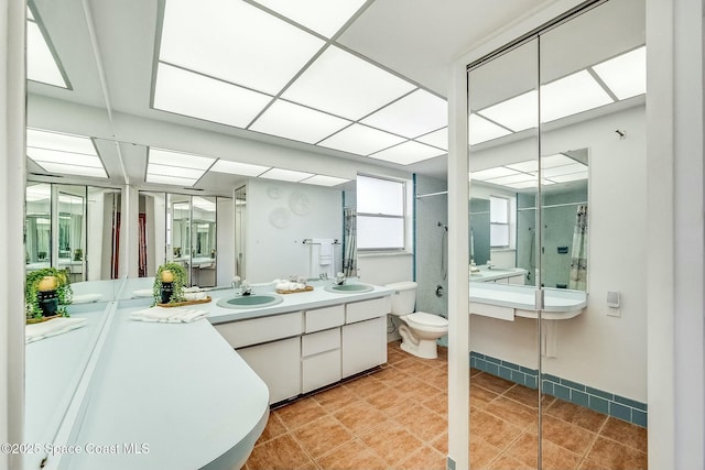 bathroom featuring double vanity, a shower stall, toilet, and a sink