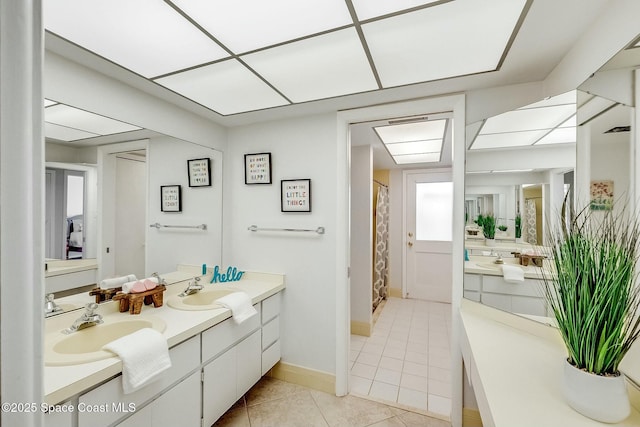 full bathroom with a sink, baseboards, double vanity, and tile patterned floors