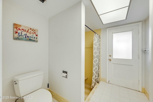 bathroom with curtained shower, toilet, and baseboards