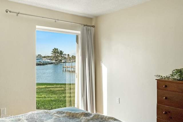 bedroom featuring a water view and a textured ceiling