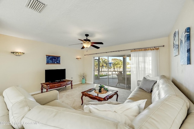 living area featuring a textured ceiling, a ceiling fan, visible vents, and baseboards