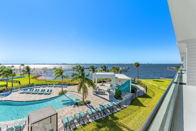 pool featuring a yard, fence, a patio, and a water view