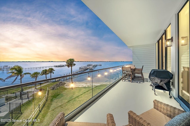 balcony at dusk with area for grilling and a water view