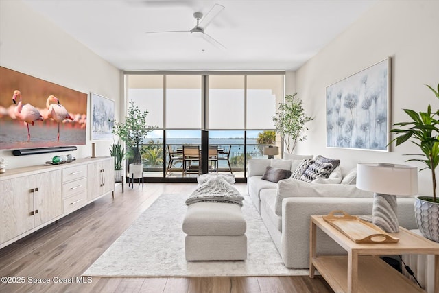 living area with floor to ceiling windows, wood finished floors, and ceiling fan