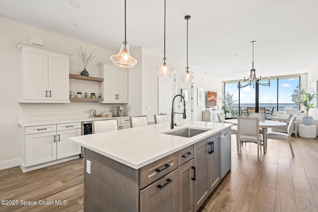 kitchen with light wood-type flooring, a sink, open shelves, white cabinets, and a wall of windows