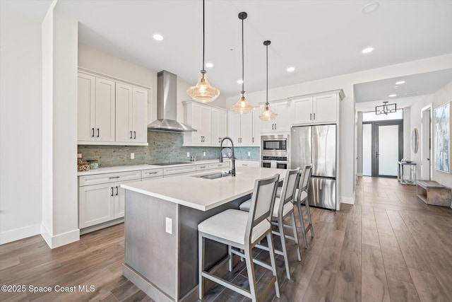 kitchen with light countertops, wall chimney range hood, tasteful backsplash, and appliances with stainless steel finishes