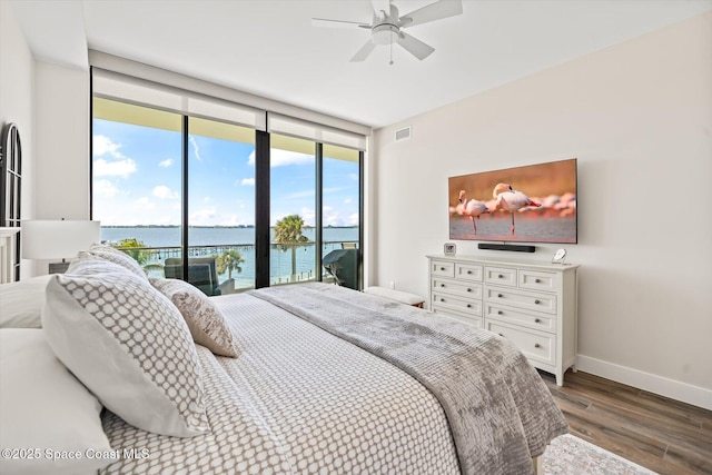 bedroom featuring visible vents, baseboards, a wall of windows, wood finished floors, and access to outside