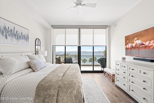 bedroom with light wood finished floors, visible vents, access to exterior, ceiling fan, and floor to ceiling windows