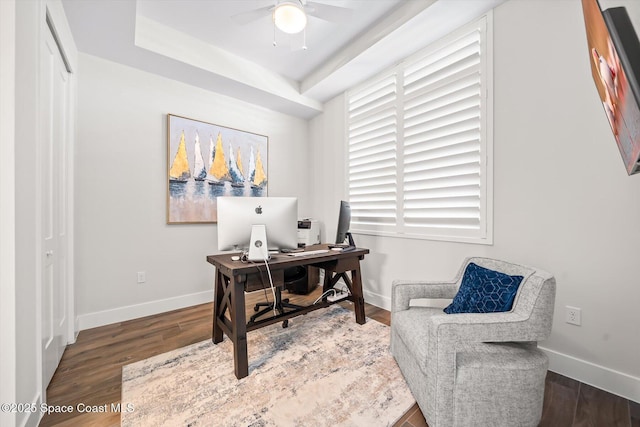 office space with a ceiling fan, a raised ceiling, baseboards, and wood finished floors