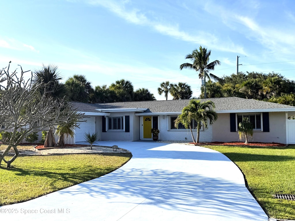 ranch-style home with stucco siding, roof with shingles, concrete driveway, a front yard, and an attached garage