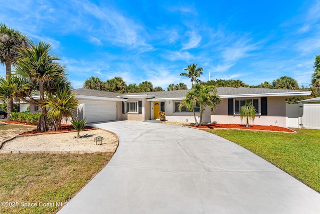 ranch-style house featuring fence, concrete driveway, a front yard, stucco siding, and an attached garage