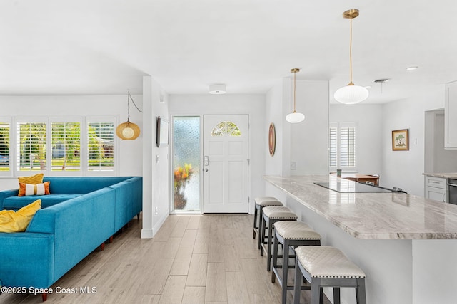 kitchen with plenty of natural light, light wood-style flooring, a breakfast bar, and black electric stovetop