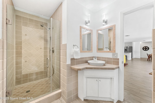 bathroom with vanity, a shower stall, and wood finished floors